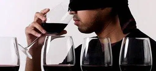 a man sniffing a glass of red wine