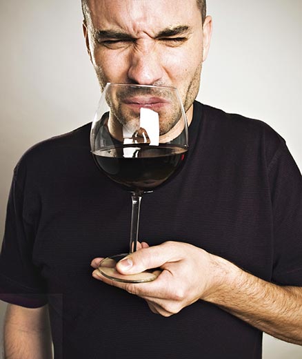 a man holding a glass of spoilt red wine